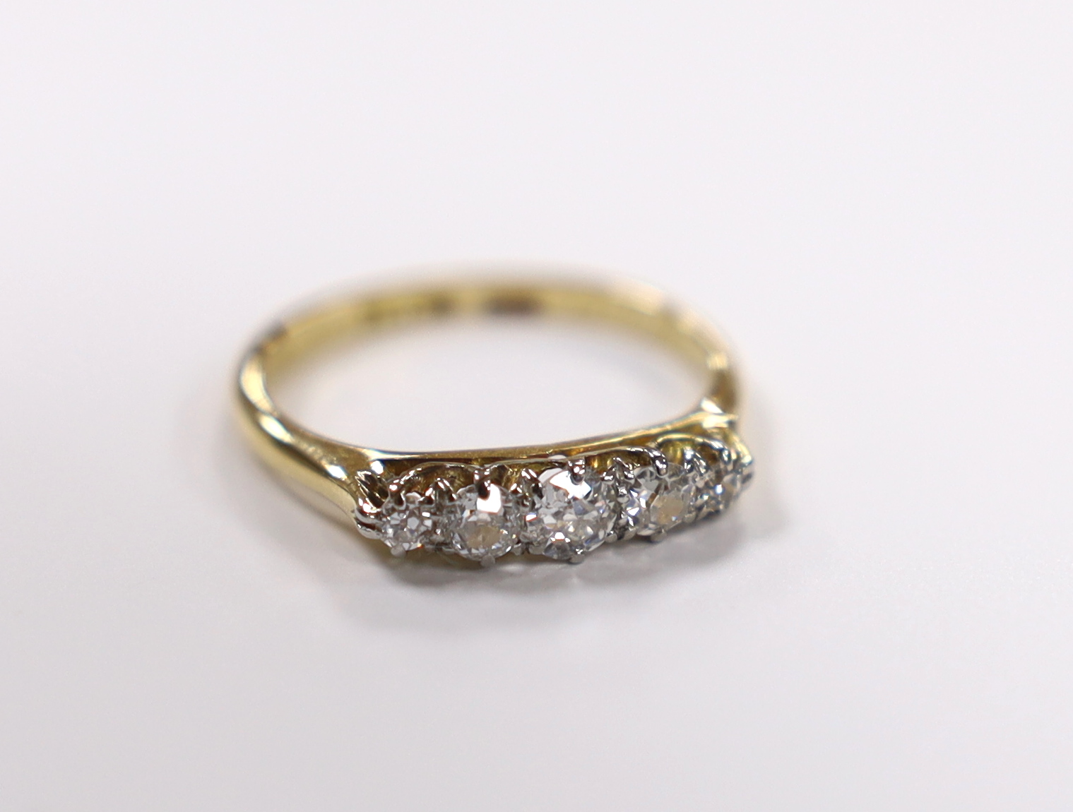 A 1920's 18ct, plat and graduated five stone diamond set half hoop ring, size K/L, gross weight 2.6 grams.